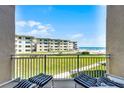 Enjoy the amazing beachfront view from this cozy balcony with chairs and beautiful green space at 4821 Saxon Dr # 201B, New Smyrna Beach, FL 32169