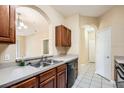 Open kitchen with stainless steel sink and black dishwasher looking into the living and dining rooms at 6402 Cava Alta Dr # 107, Orlando, FL 32835