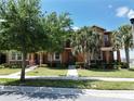 Charming townhome exterior featuring lush landscaping, sidewalk and a beautiful outdoor space with palm trees at 6524 Calamondin Dr, Winter Garden, FL 34787