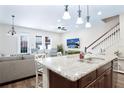 Bright kitchen with a large granite island, stainless sink, pendant lighting, and staircase access at 6524 Calamondin Dr, Winter Garden, FL 34787