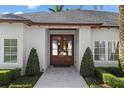 Elegant front entrance with custom wood door framed by symmetrical landscaping and a neutral color palette at 1020 Mayfield Ave, Winter Park, FL 32789