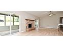 Cozy living room showcasing a brick fireplace, ceiling fan, and sliding glass doors that lead to the screened patio at 1025 Winter Springs Blvd, Winter Springs, FL 32708
