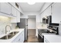 Modern kitchen featuring white cabinets, stainless steel appliances, and stylish backsplash at 1140 S Orlando Ave # E-1, Maitland, FL 32751