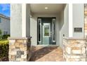 Inviting front entrance with a decorative glass door, stone pillars, and brick paver walkway at 321 Falls Dr, Kissimmee, FL 34747