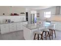 Modern kitchen features white cabinetry, stainless steel appliances, tile backsplash and a marble waterfall island at 4443 Doris Dr, New Smyrna Beach, FL 32169
