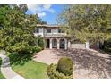 Beautiful two-story home with a brick driveway, three-car garage, and covered front porch, surrounded by trees and green lawn at 6313 Bordeaux Cir, Sanford, FL 32771