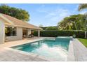 Backyard pool and spa surrounded by a brick patio, lush landscaping, and a covered sitting area perfect for entertaining at 652 Rochester St, Oviedo, FL 32765