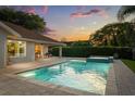 Backyard pool and spa surrounded by a brick patio, lush landscaping, and a covered sitting area perfect for entertaining at 652 Rochester St, Oviedo, FL 32765