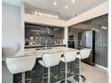 Modern kitchen island has white leather bar stools and features a marble countertop with a drop-down chandelier at 748 Desert Mountain Ct, Reunion, FL 34747
