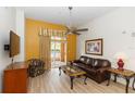 Bright living area featuring sleek wood floors, complemented by a ceiling fan and sliding glass doors to the balcony at 8100 Poinciana Blvd # 2109, Orlando, FL 32821