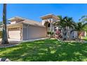 Beautiful home featuring lush green lawn, mature palms, and an arched entrance with modern architectural accents at 902 Wingate Trl, Port Orange, FL 32128