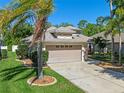 Attractive front exterior view of home with a two-car garage, palm trees, and well-maintained landscaping at 902 Wingate Trl, Port Orange, FL 32128