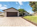 Beautiful home featuring a brick paved driveway, two-car garage, manicured lawn, and mature trees at 9338 Palm Tree Dr, Windermere, FL 34786