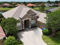 Stunning aerial view of a beige home with tile roof, brick driveway and a pond in the backyard at 1027 Algare Loop, Windermere, FL 34786