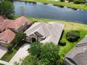 Aerial view of a beige home with lush landscaping and a serene lake view in the back at 1027 Algare Loop, Windermere, FL 34786