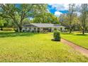 Quaint single-story home with a large tree, mature plantings and walkway leading to the front door at 20 Stone Gate S, Longwood, FL 32779