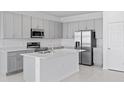 Bright kitchen with stainless steel appliances, gray cabinets, and a spacious island with a sink at 2030 Firethorn Loop, Haines City, FL 33844