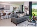Open living space with a gray sofa, modern decor, an adjacent kitchen, and a view of the backyard at 2030 Firethorn Loop, Haines City, FL 33844