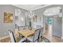 Bright dining room featuring a wooden table, six cushioned chairs, and modern chandelier open to kitchen area at 250 Shady Oaks Cir, Lake Mary, FL 32746