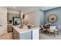 Kitchen with a stainless steel refrigerator, island with sink, pendant lighting, and adjacent dining area at 2576 Penguin Blvd, Davenport, FL 33837