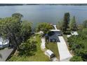 Aerial view of property with lake access and a dock with lake views surrounded by mature trees and greenery at 30 Sunset Cir, Lake Alfred, FL 33850