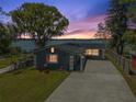 Beautiful exterior view of the home with a large driveway and a serene lake view at sunset at 30 Sunset Cir, Lake Alfred, FL 33850