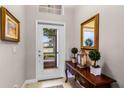 Welcoming foyer featuring a decorative table, mirror, and view of the outdoors through a glass-paneled front door at 3714 Marigot Way, Clermont, FL 34711