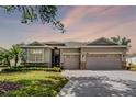 Charming single-story home with a three-car garage, stone accents, and manicured landscaping at dusk at 3714 Marigot Way, Clermont, FL 34711