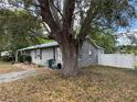 Side view of the home, showing the stucco exterior, mature trees, and a partial view of the fenced backyard at 3845 Sw 148Th Pl, Ocala, FL 34473