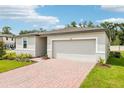 Attractive single-Gathering home featuring a two-car garage, brick driveway, and well-kept lawn at 4701 Jasmine Cir, Leesburg, FL 34748
