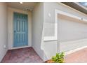 Close-up of a charming blue front door and brick walkway, with a glimpse of the garage at 4701 Jasmine Cir, Leesburg, FL 34748