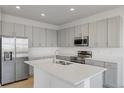 Modern kitchen featuring stainless steel appliances, gray cabinetry, and a center island with a double sink at 527 Silver Palm Dr, Haines City, FL 33844