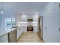 Well-lit kitchen featuring white cabinets, stainless steel appliances, and light-colored wood flooring at 7651 Whisper Way # 104, Reunion, FL 34747