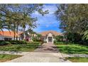 Charming one-story home with a well-manicured lawn, lush landscaping, and a brick driveway leading to the entrance at 11139 Camden Park Dr, Windermere, FL 34786