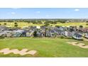 An aerial view shows homes lining a golf course with sand traps and the surrounding community at 1539 Corolla Ct, Reunion, FL 34747