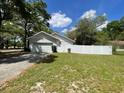 View of the side of the home, featuring a two-car garage, white picket fence and green lawn at 25721 Pinehurst St, Sorrento, FL 32776