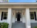 Charming front entrance features a black door, sidelights, sconces and classic columns at 25721 Pinehurst St, Sorrento, FL 32776