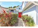 Inviting front entrance with a bright red door, framed by lush greenery, and an arched window above at 271 Morning Glory Dr, Lake Mary, FL 32746