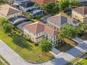 A stunning aerial view of a luxurious two-story home with a terra cotta tile roof, manicured lawn, and mature trees at 4200 Oaktree Dr, Davenport, FL 33837