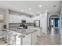 Bright kitchen features white cabinets, granite countertops, stainless appliances, and an eat-in island with barstool seating at 4200 Oaktree Dr, Davenport, FL 33837