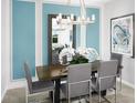 Elegant dining area featuring modern lighting, a large mirror and lovely blue accent wall at 503 Silver Palm Dr, Haines City, FL 33844
