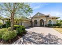 Beautiful home featuring a brick driveway, arched entryway, and mature landscaping at 5509 Meadow Hill Loop, Lady Lake, FL 32159