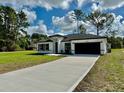 Attractive single-Gathering home with a well-kept green lawn, an extended driveway, and black trim at 6872 Sw 132Nd Pl, Ocala, FL 34473
