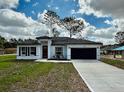 Charming single-story house with a neatly manicured lawn, a long driveway, and a covered entryway at 6872 Sw 132Nd Pl, Ocala, FL 34473