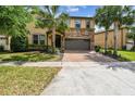 Charming two-story home with a stone facade, a two-car garage, and mature palm trees in the front yard at 8808 Macapa Dr, Kissimmee, FL 34747