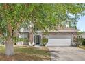 Two-story home with stone accents, a two car garage and a shade tree in the front yard at 9919 Cypress Knee Cir, Orlando, FL 32825