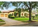 Charming Mediterranean home featuring lush green lawn, mature trees and a brick driveway at 11055 Ullswater Ln, Windermere, FL 34786