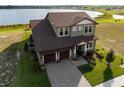 Aerial view of a two-story home showcasing manicured lawn, a three-car garage, and lake views at 200 Valencia Ridge Dr, Auburndale, FL 33823