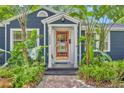 Inviting front entrance with a vibrant orange door, complemented by lush tropical landscaping at 2004 E Marks St, Orlando, FL 32803
