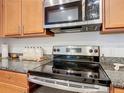 Close-up of modern stainless steel stove with smooth cooktop and microwave above granite countertops at 332 Blue Lake Cir, Kissimmee, FL 34758